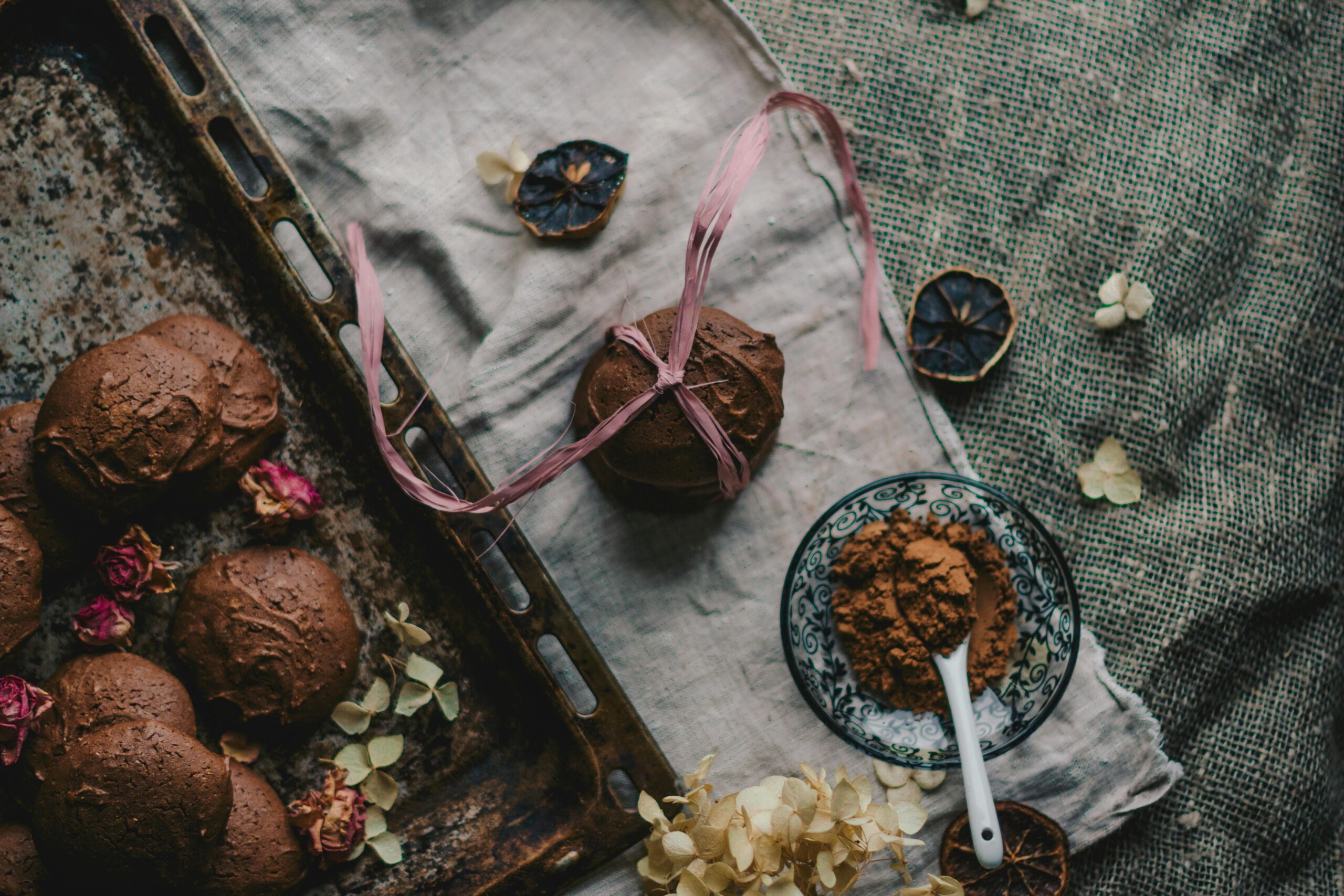 Artistic flat lay of chocolate pastries with cocoa and dried flowers.